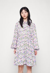 Vestido de manga longa em lilás claro com padrões florais em rosa, verde e azul. Apresenta um decote com gola e uma cintura franzida.