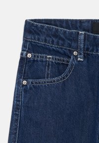 Mørkeblå denimjeans med høy midje, kontrastsøm, en frontlomme med metallnagler og en jevn tekstur.