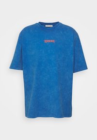 Blå bomull t-shirt med avslappnad passform, korta ärmar och rundad halsringning. Har en liten röd textlogo med "LES BENJAMINS" på bröstet.