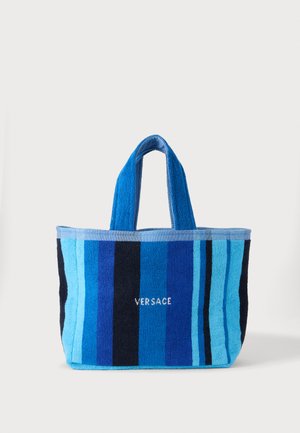 Modrá pruhovaná taška s krátkymi rukoväťami a vyšitým bielym logom „Versace“ na prednej strednej časti.