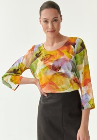 Multikleurige, lichte blouse met een ronde halslijn en driekwartmouwen, met een aquarelpatroon in groen, oranje en paars.