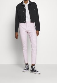 Veste en denim noir, chemise blanche à boutons, pantalon à carreaux rose et blanc, baskets montantes noires avec semelle et lacets blancs.