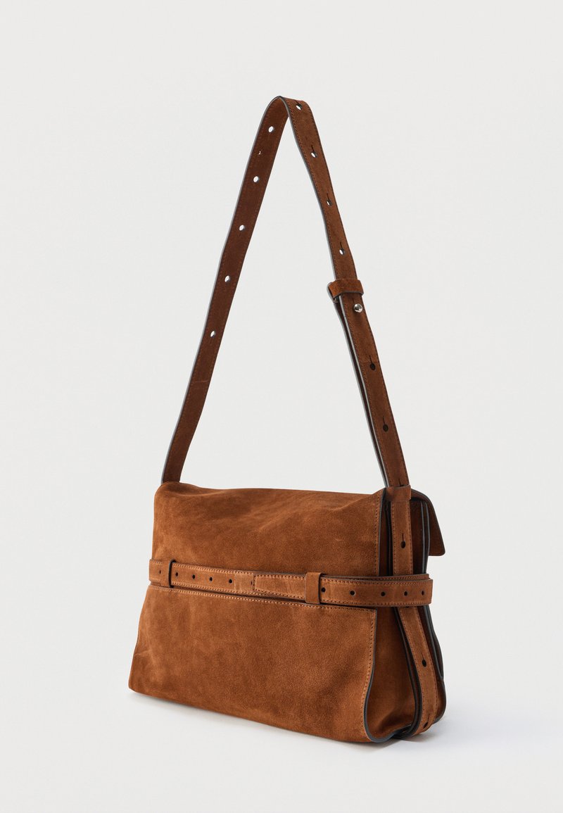 Sac bandoulière en daim marron avec bandoulière réglable et détail de ceinture décorative sur le devant, présenté sur un fond uni.