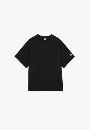 T-shirt noir à manches courtes et col rond avec une petite écusson circulaire sur la manche gauche.