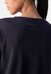 Navyblauwe katoenen t-shirt met ronde halslijn, voorzien van een subtiele merklabel op de achterkant. Gladde textuur en een relaxte pasvorm.