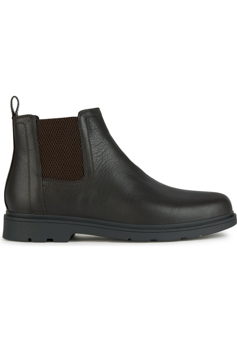 Bota Chelsea de cuero marrón con un panel de malla texturada, una lengüeta y una suela de goma duradera, diseñada para facilitar su uso y proporcionar comodidad.