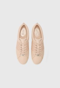 Beige sneakers met een leren en stoffen bovenkant, voorzien van een patroonzijde, vetersluiting, gewatteerde kraag en logoaccent op de tong.