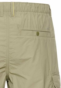 Beige shorts gemaakt van lichtgewicht stof. Voorzien van een elastische tailleband, een achterzak met een knoop en gestikte details.
