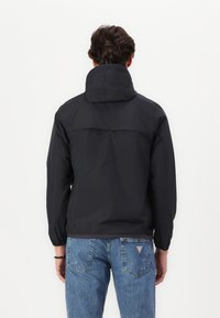 Black lightweight jacket with a hood, featuring a smooth, matte texture and elastic cuffs. Back has a seam detail and a relaxed fit.