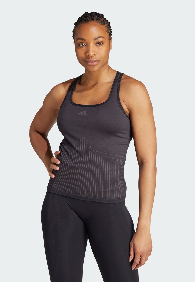 Canottiera atletica grigio scuro con design a schiena scoperta, caratterizzata da righe verticali e logo Adidas sul petto. Taglio aderente, materiale elastico.