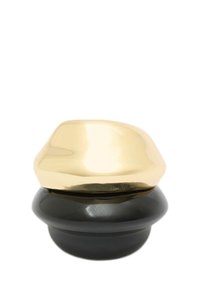 Contenant rond avec une base noire brillante et un couvercle doré brillant. Le couvercle a une forme organique, créant un contraste visuel doux.