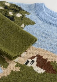 Pull en tricot avec un fond bleu et des motifs d'arbres et de maisons verts, en mélange de laine texturé, col rond et poignets côtelés.