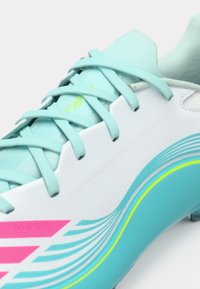 Το ανοιχτό μπλε ποδοσφαιρικό παπούτσι διαθέτει λευκό σώμα με ροζ και γαλάζιες πινελιές, υφασμένο κολάρο και πολύχρωμα σχέδια στη σόλα.