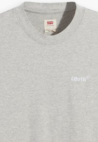 Pelēka kokvilnas T-krekli ar apaļu kaklu, kuram uz kreisā krūšu laukuma ir balts izšūts "Levi's" logo. Mīksta tekstūra, ikdienišķs dizains.