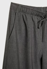 Ciemnoszare, lekkie spodnie z tkaniny, z elastycznym paskiem w talii, detalem sznureczka i bocznymi kieszeniami, charakteryzujące się gładką teksturą.