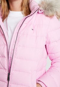 Helle rosa Pufferjacke mit Reißverschluss, gerippten Bündchen und abnehmbarem Kunstfellkragen. Markenlogo auf der Brust und seitlichen Reißverschlusstaschen.