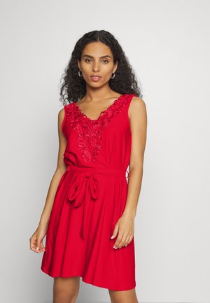 Vestido vermelho sem mangas com decote em V, apresentando detalhes florais bordados ao redor do decote e um cinto na cintura para uma silhueta ajustada.