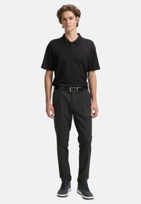 Fekete pólóing, gallérral és három gombos légkört középen, sötétszürke szabott nadrággal és tengerészkék sportcipővel kombinálva. Öv is benne van.