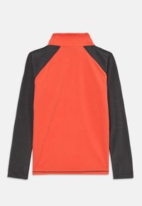 Pull en polaire orange vif avec des manches noires. Doté d'un col montant et d'une double couture le long de l'ourlet et des coutures. Texture lisse.