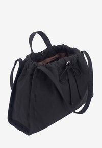 Sac fourre-tout en tissu noir avec fermeture à cordon, deux poignées courtes et une longue bandoulière, présenté ouvert avec une doublure intérieure marron.