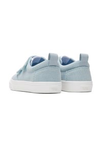 Lichtblauwe canvas sneakers met witte rubberen zolen, een textuur op het oppervlak en twee trekflappen aan de achterkant. Opvallende branding op de hak.