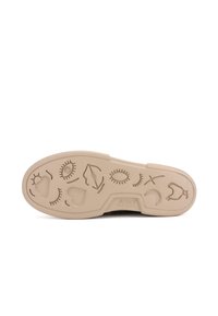 Beige rubber shoe sole featuring various embossed patterns, including eyes, lips, hearts, and leaves, with a textured finish.