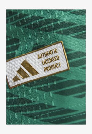 Groene stof met een textuurpatroon; heeft een witte patch met "AUTHENTIC LICENSED PRODUCT" en een gouden Adidas-logo ontwerp.