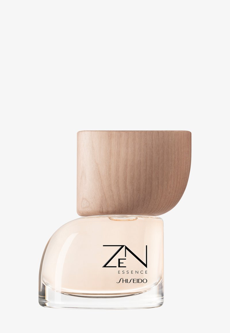 Flacon de parfum en verre contenant un liquide beige clair, texte minimaliste noir "ZEN Essence Shiseido", et grand bouchon en bois courbé.