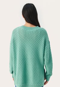 Menta zöld, oversized kötött pulóver texturált mintával, bordás nyakkivágással és mandzsettákkal, oldalsó hasítékokkal és laza szabással, hátulról nézve.