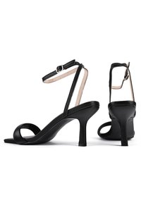 Schwarze Leder High-Heel Sandalen mit einem schlanken Knöchelriemen, offener Zehenpartie und geschwungenem Vorderdesign. Mattes Finish und minimalistisches Silhouette.