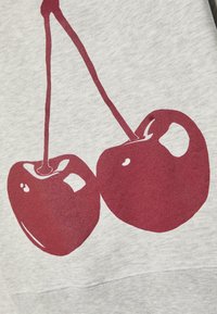 Tissu de sweat-shirt gris avec un imprimé graphique de deux cerises rouges avec des reflets brillants. Le design comprend des tiges proéminentes et des formes arrondies.
