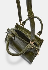 Zelena usnjena torbica s kroko vzorcem, opremljena z dvema ročajema in nastavljivim trakom. Zlato obarvana strojna oprema in zadrga.