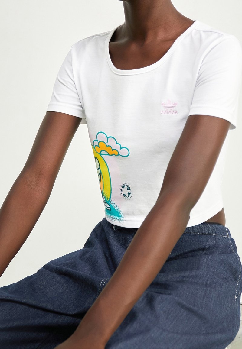 Vitt kortärmad t-shirt med rund halsringning, prydd med en färgglad grafik av en gul sol och moln. Materialet verkar slätt och bomullsliknande.