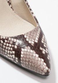 Escarpin à bout pointu en simili-cuir texturé de serpent dans des nuances de marron et de crème, avec une finition brillante et une semelle noire.