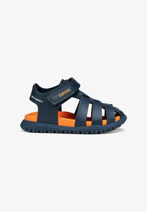 Sandalo bambino blu navy con cinturini chiusi sulle dita, soletta imbottita arancione, cinturino in velcro regolabile e suola robusta per uso esterno.