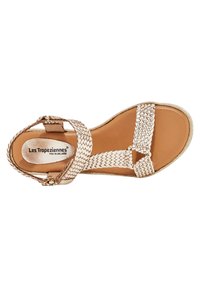 Vävd remsandaler i ljusbeige med platt sula, med justerbar ankelrem och rund spänne. Slät läderinnersula, avslappnad design.