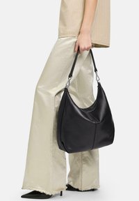 Borsa hobo in pelle nera con una texture liscia e una forma curvilinea, dotata di una tracolla nera e dettagli in hardware argentato.