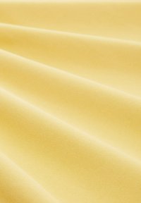 Mjuk gul tyg med en jämn textur, med en subtil, fin väv och försiktigt draperade veck. Idealisk för olika textileapplikationer.