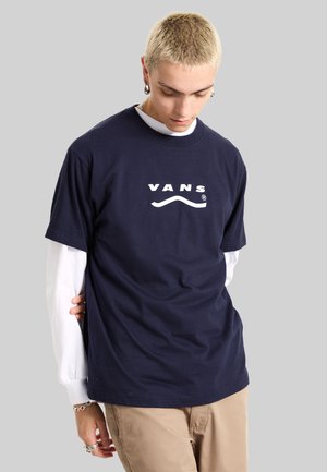 Camiseta de algodón azul marino con un logo blanco de "VANS" con un acento curvado. Mangas cortas y un diseño clásico de cuello redondo.