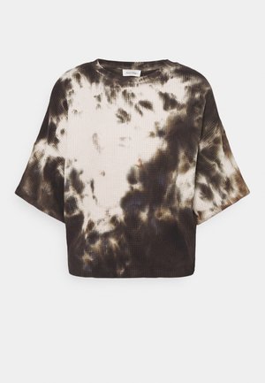 Kort mouw wafelgebreide top met zwart-wit tie-dye patroon en ronde halslijn op een witte achtergrond.