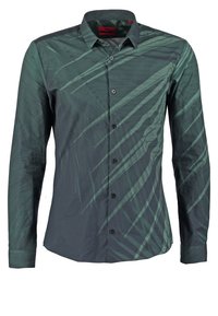 Chemise à manches longues vert foncé, boutonnée, avec un motif subtil de rayures diagonales abstraites et un col pointu.