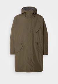 Casaco impermeável verde oliva com capuz, botões de pressão, bolsos laterais e um interior forrado em xadrez. Apresenta um corte descontraído e cordões ajustáveis.