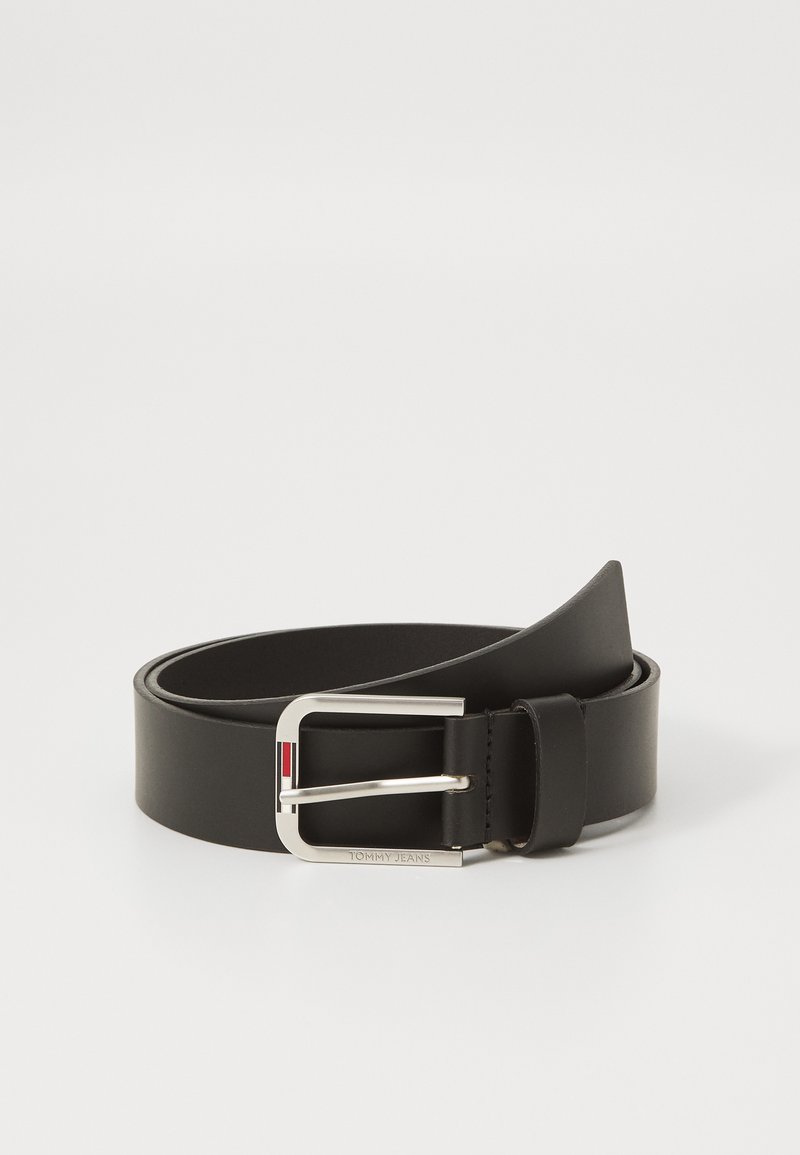 Ceinture en cuir noir avec une boucle rectangulaire en argent. La boucle présente un accent rayé rouge et blanc. Texture lisse, design classique.