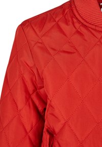 Röd vadderad jacka med ribbad krage. Har ett diamantmönster och en mjuk textur. Inkluderar sidoficka och synliga sömnadsdetaljer.