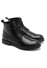 Czarne skórzane botki za kostkę z okrągłym noskiem, sznurowanym przodem i pętelką do zakupu. Teksturowana skórzana cholewka z gumową podeszwą dla lepszej przyczepności.