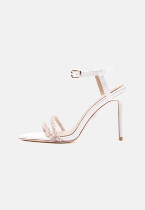 White high-heeled sandal with thin ankle strap, pointed toe, and two front straps decorated with pearls.