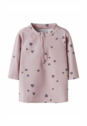 Chemise pour tout-petit à manches longues rose clair avec une fermeture éclair à l'avant et des motifs de cœurs gris foncé dispersés.