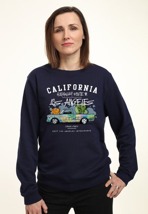 Námořnická modrá mikina s grafickým potiskem náklaďáku s barevným graffiti; text obsahuje "Kalifornie" a "Los Angeles."
