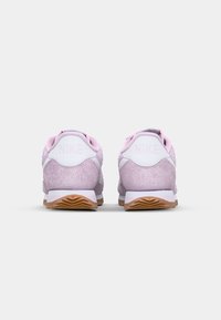 Pink suede sneakers with white accents, featuring padded collar, textured rear, and light brown rubber outsole with patterned tread.
