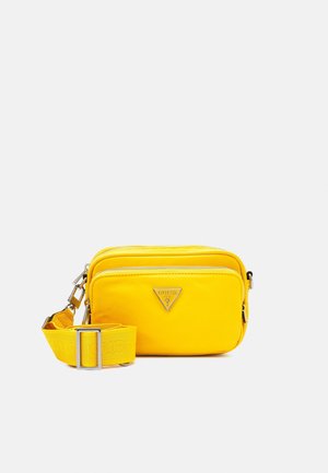 Felgele compacte crossbodytas met twee ritssluitingsvakken en verstelbare riem, met een klein metalen merkembleem aan de voorkant.